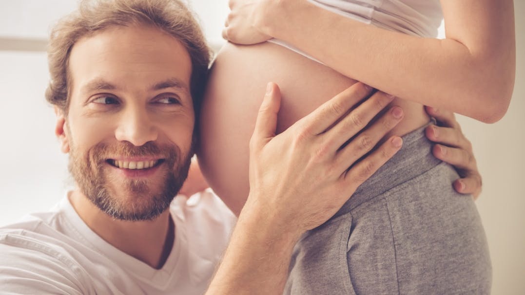 een man luistert aan de zwangere buik van een vrouw